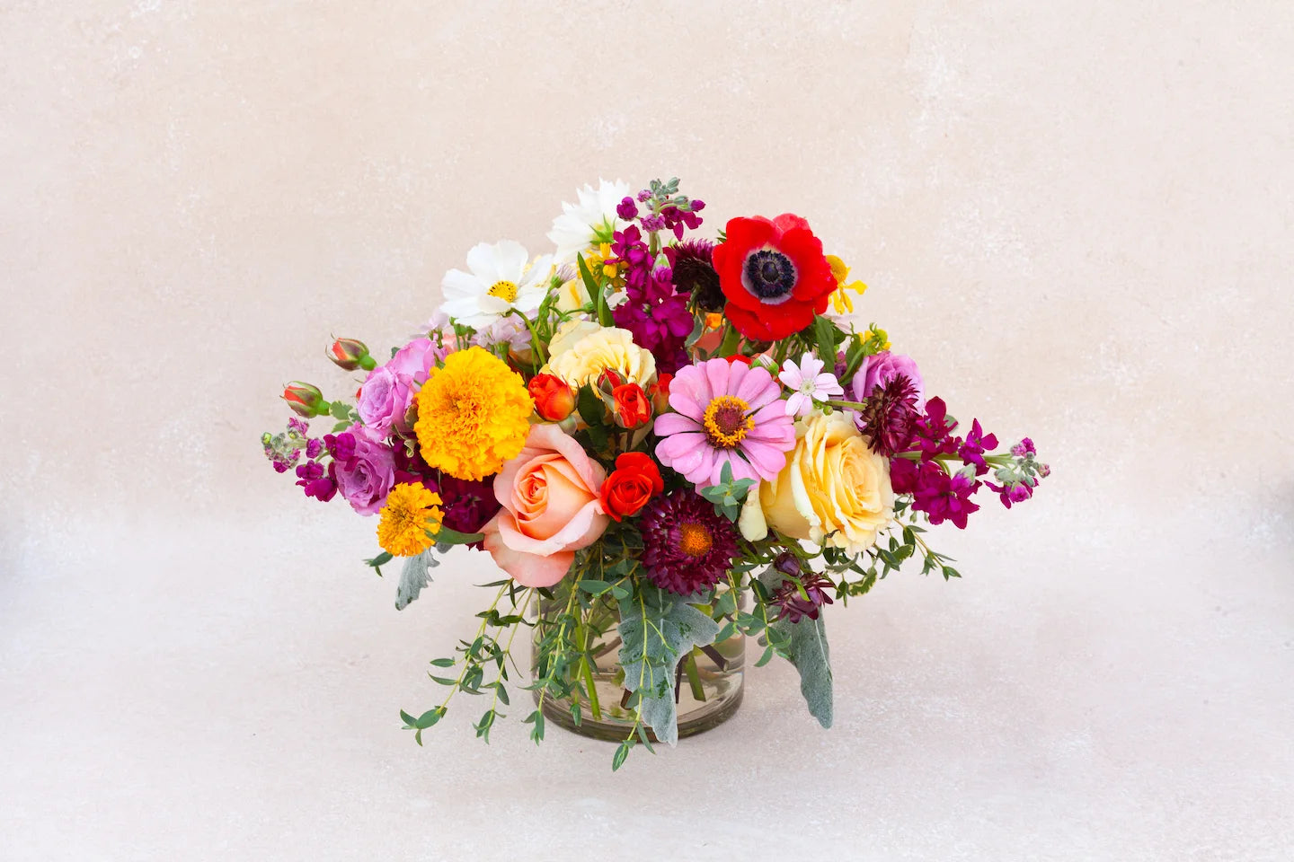 Lush garden floral arrangement with colorful flowers and a glass vase.