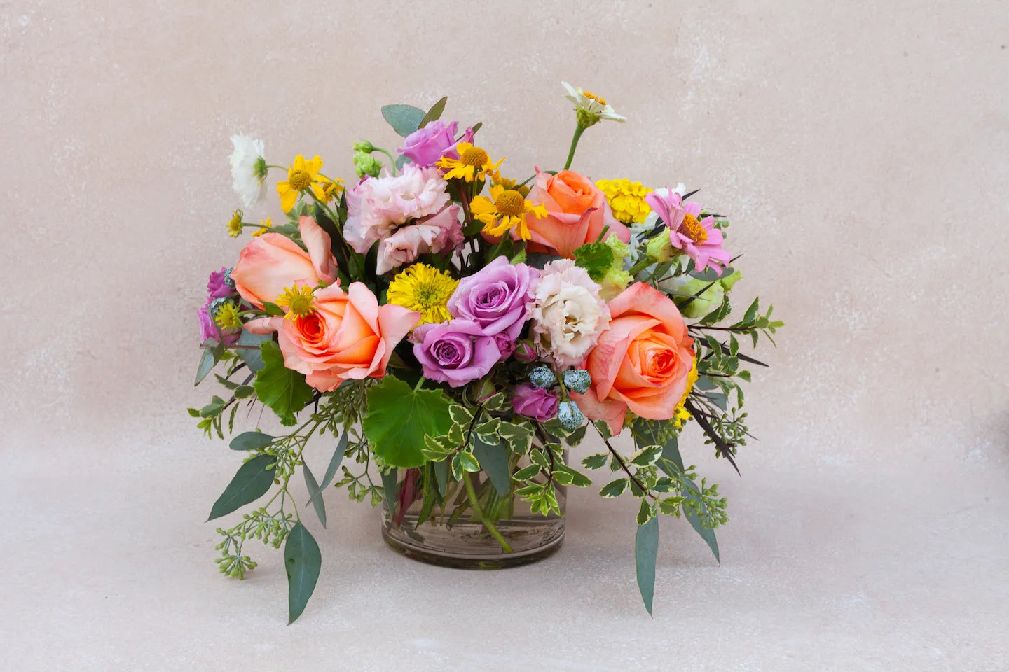 Lush garden floral arrangement with berry-toned flowers.