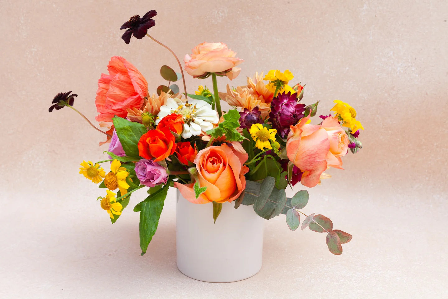 Dainty garden arrangement with colorful flowers in a white vase.