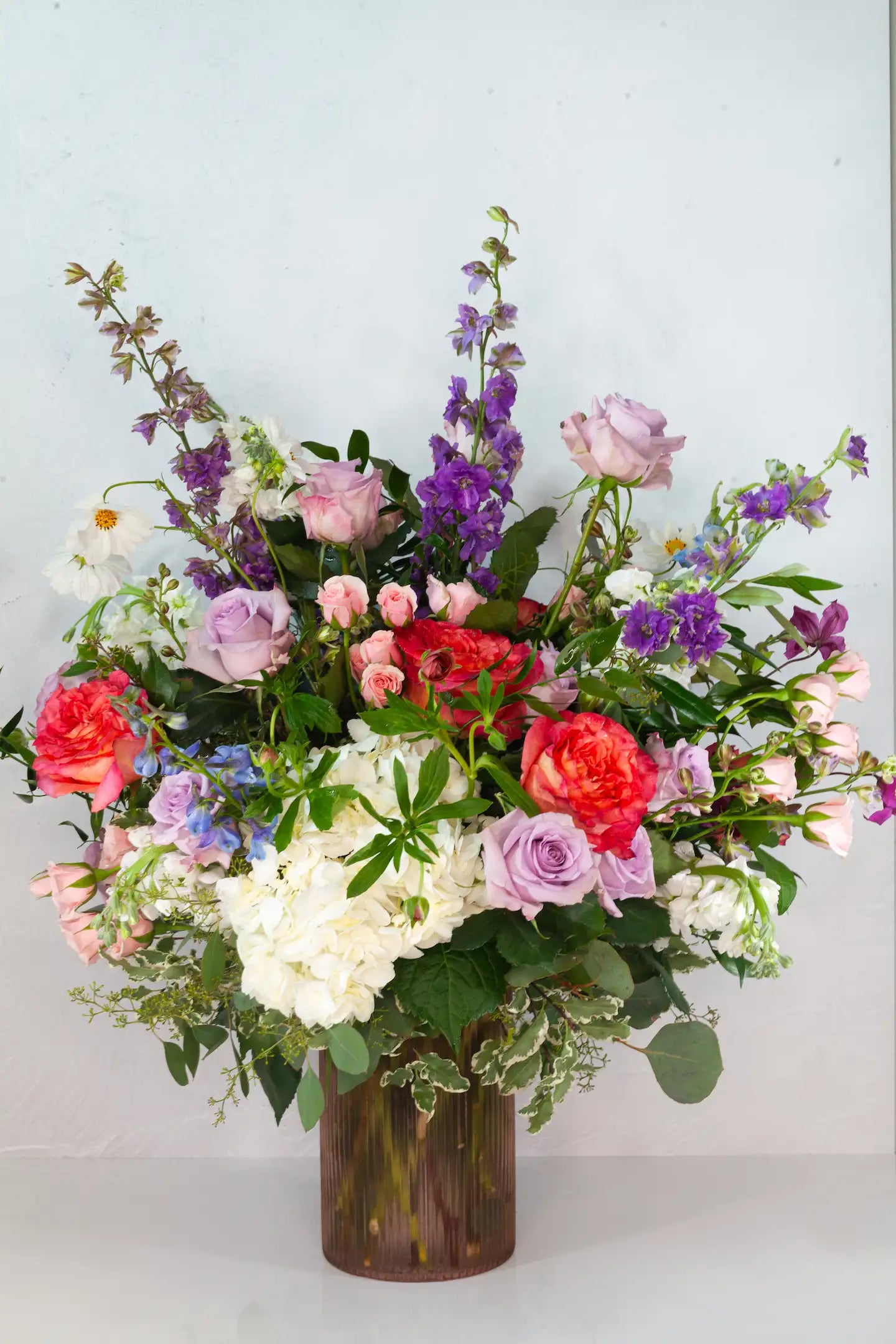 Large custom flower arrangement with bright red and purple flowers.