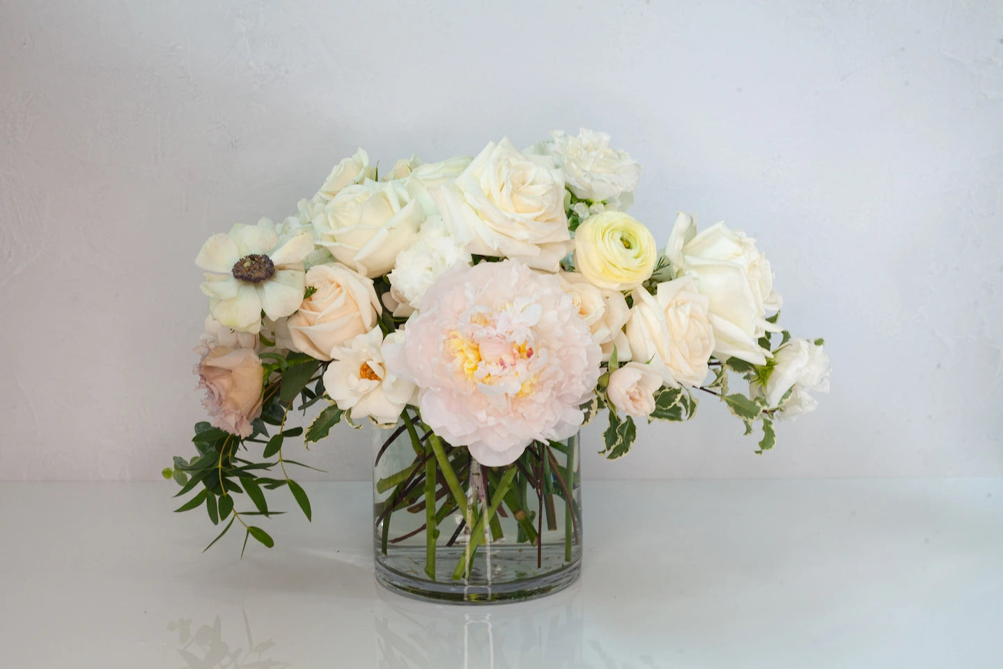 Lush garden arrangement in a glass vase with neutral flowers.