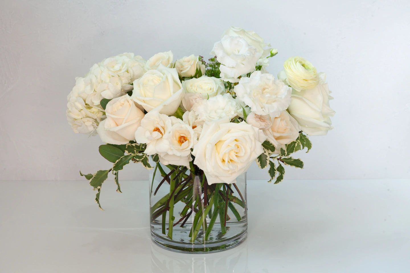 Lush garden arrangement in a glass vase with white flowers.