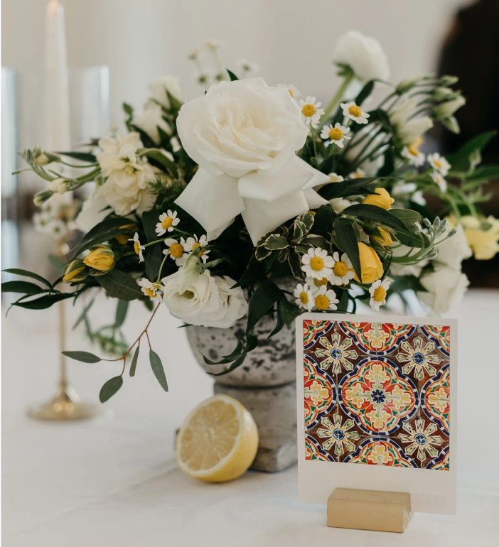 Custom white and yellow bouquet with a colorful tile in front of it.